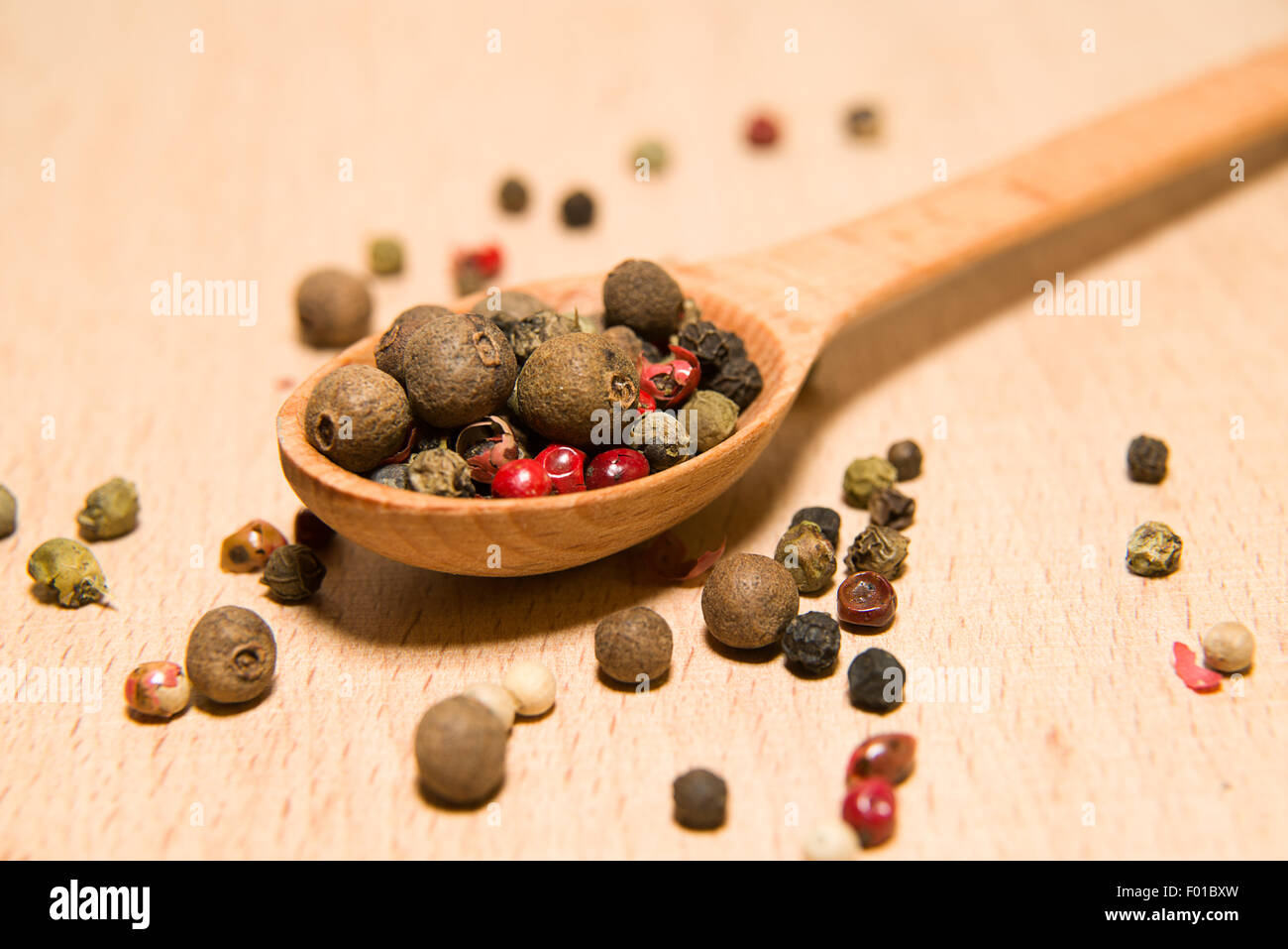 Holzlöffel, gefüllt mit einer Mischung aus Pfefferkörner sind auf eine Holzoberfläche Stockfoto