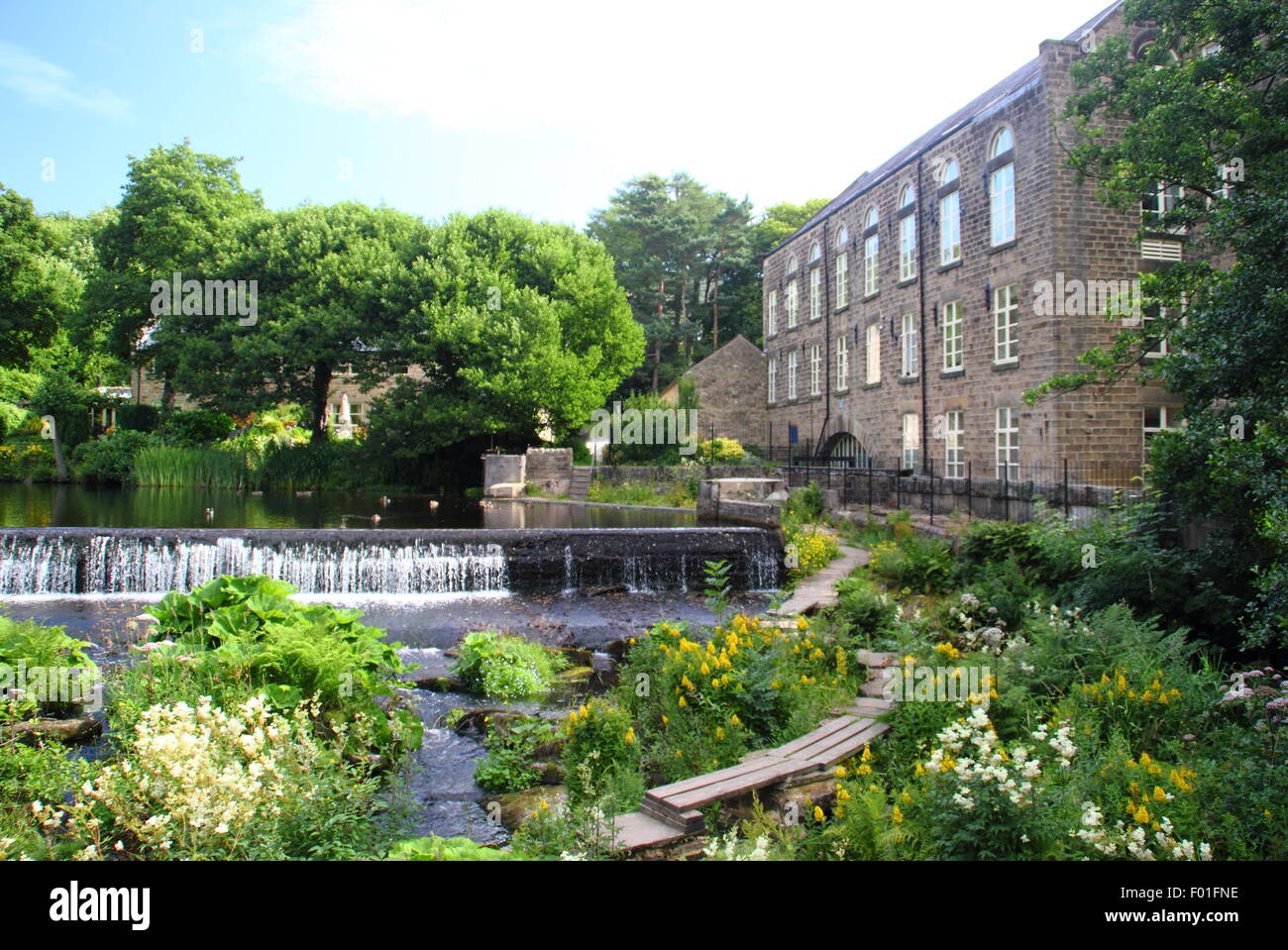 Menschen gehen über die öffentlichen Holzsteg durch Bamford Mill und Wehr in den Peak District Derbyshire England UK - Sommer Stockfoto