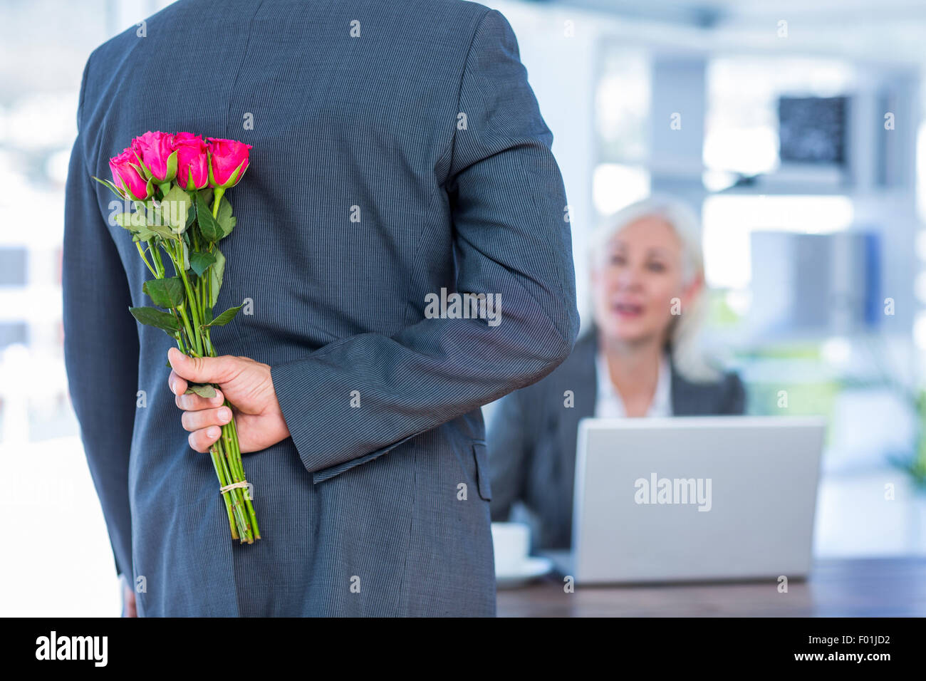 Geschäftsmann versteckt Blumen hinter Rücken für Kollegen Stockfoto