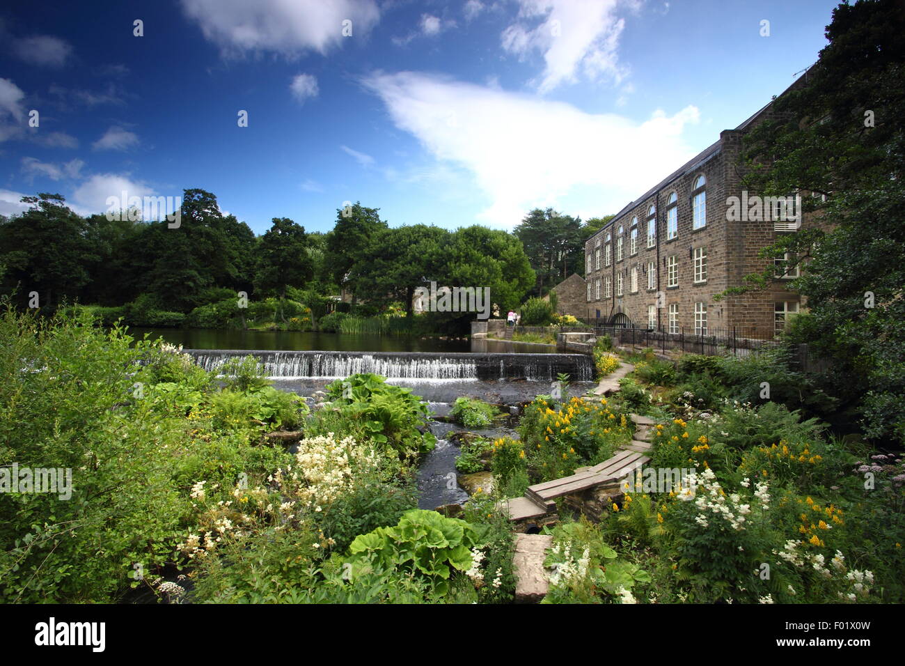 Ein Holzsteg überspannt den Fluss Derwent Bamford Mill und Wehr, Bamford, Peak District, Derbyshire England uk - Sommer Stockfoto