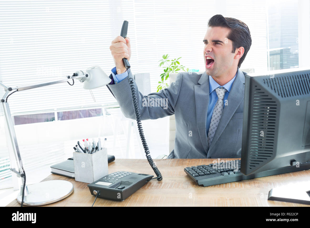 Geschäftsmann, schreien, als er hält, Telefon im Büro Stockfoto