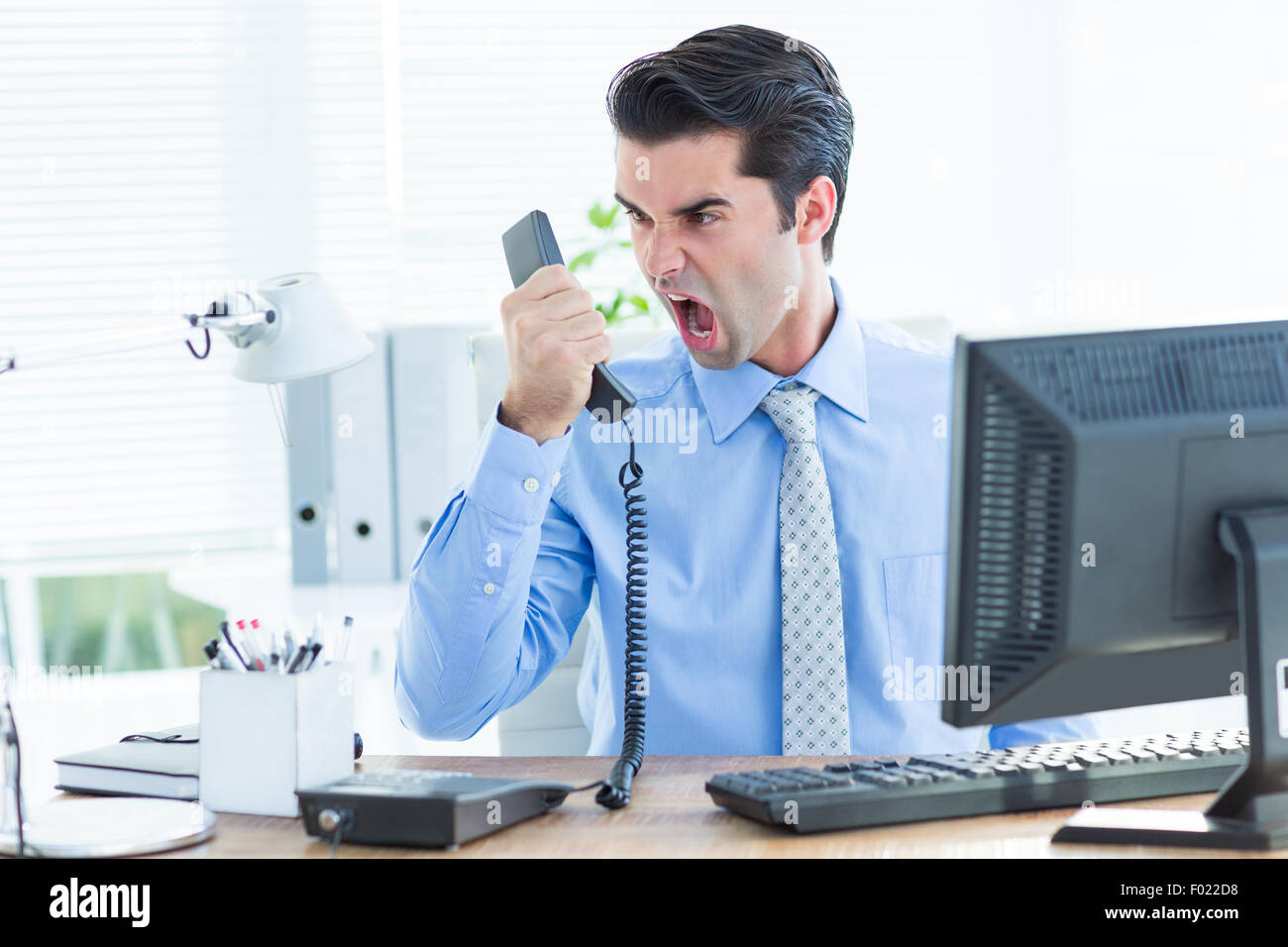 Geschäftsmann, schreien, als er hält, Telefon im Büro Stockfoto