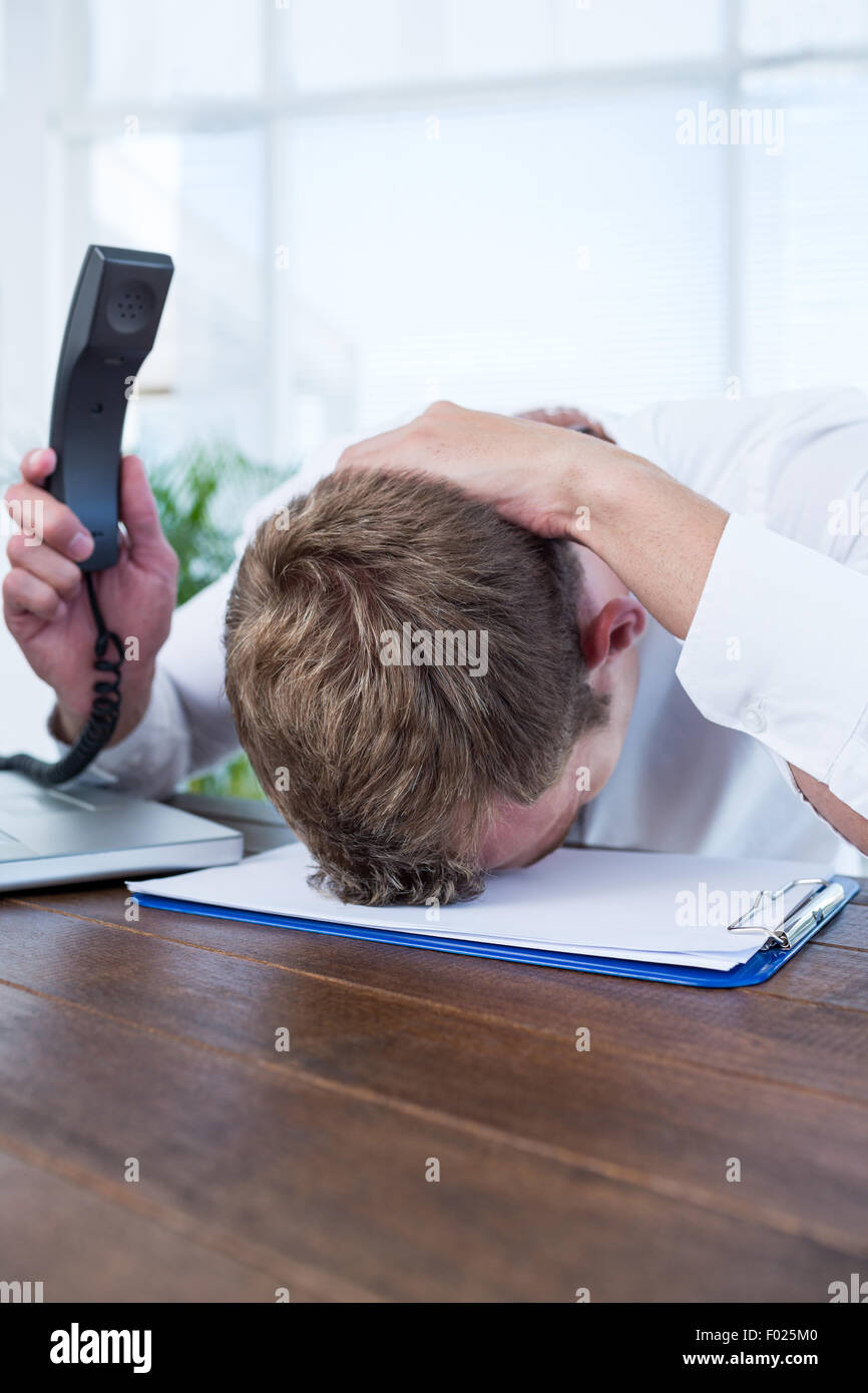 Gereizte Geschäftsmann hält ein Festnetz Telefon Stockfoto