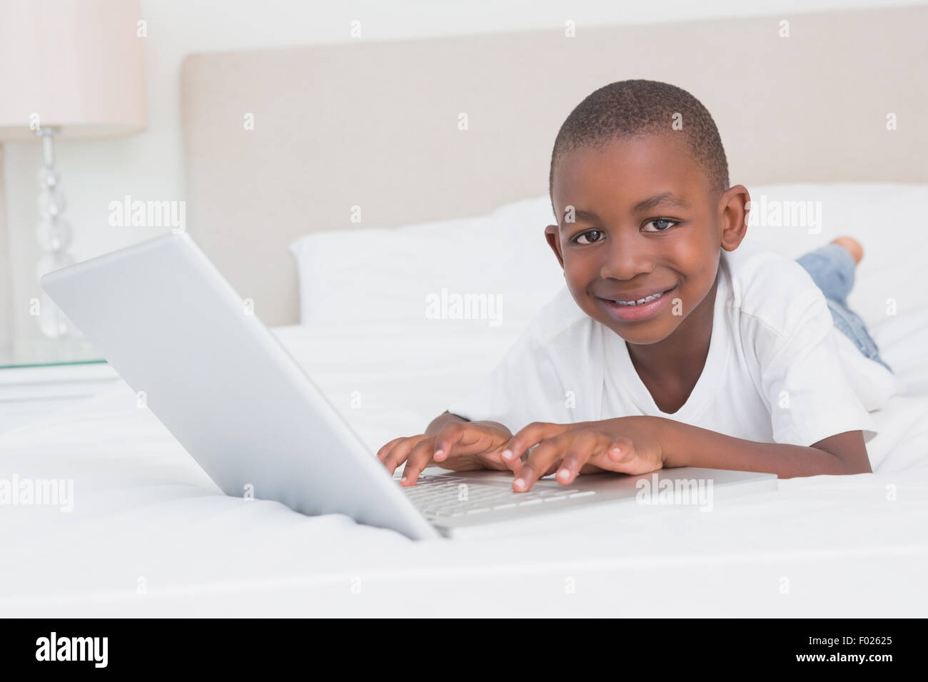 Portrait eines hübschen kleinen Jungen mit Laptop im Bett Stockfoto