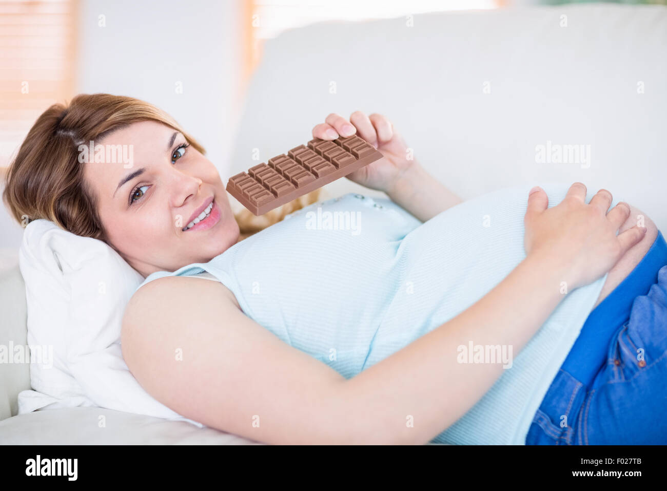 Schwangere Frau Blick in die Kamera und Schokolade zu essen Stockfoto