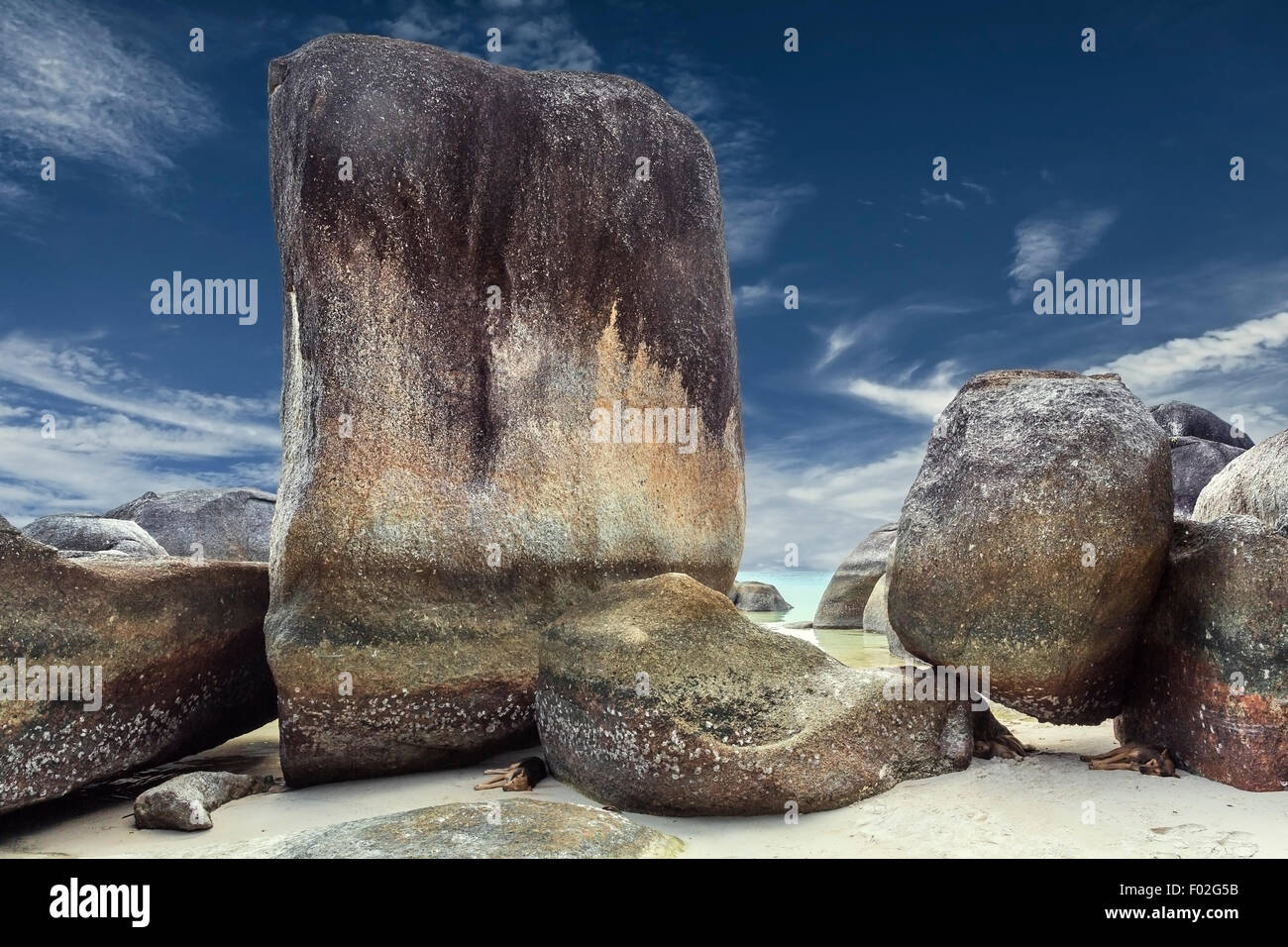 Drei Hunde schlafen am Strand im Schatten der Granitfelsen, Belitung Island, Indonesien Stockfoto