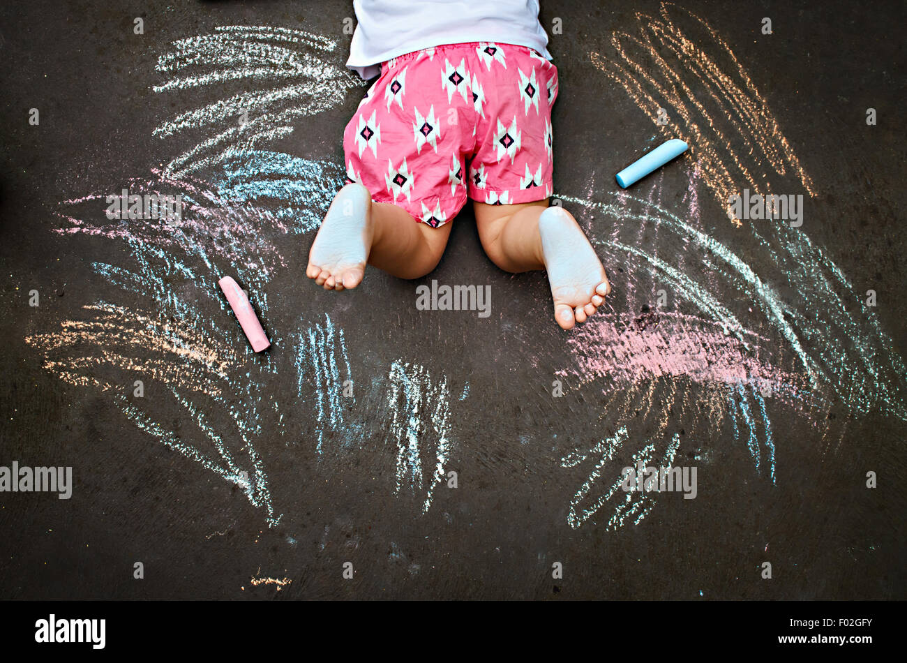 Draufsicht des Mädchens auf Boden mit Kreide zeichnen Stockfoto