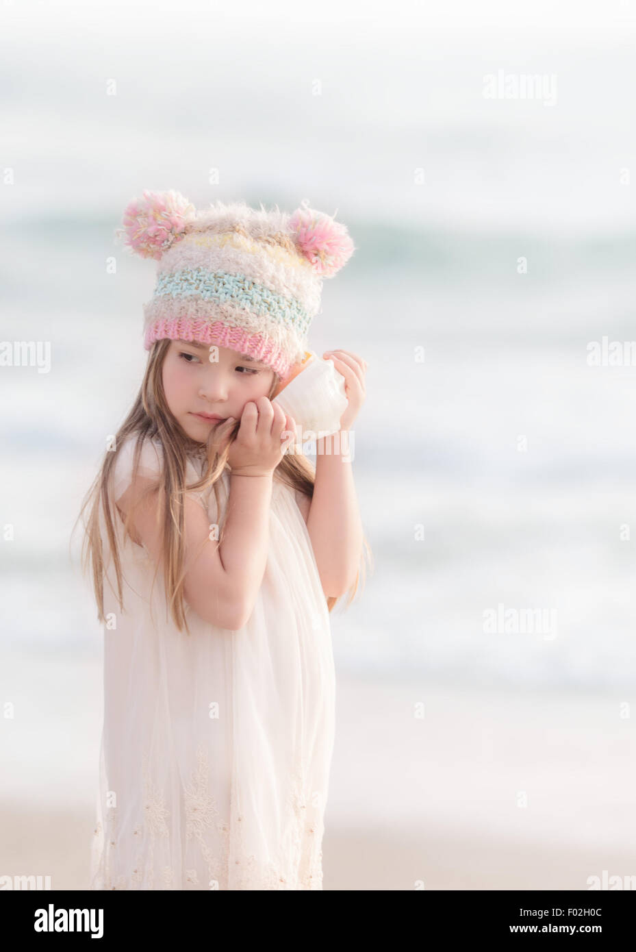 Mädchen, das am Strand steht und einer Muschel lauscht, Kalifornien, USA Stockfoto