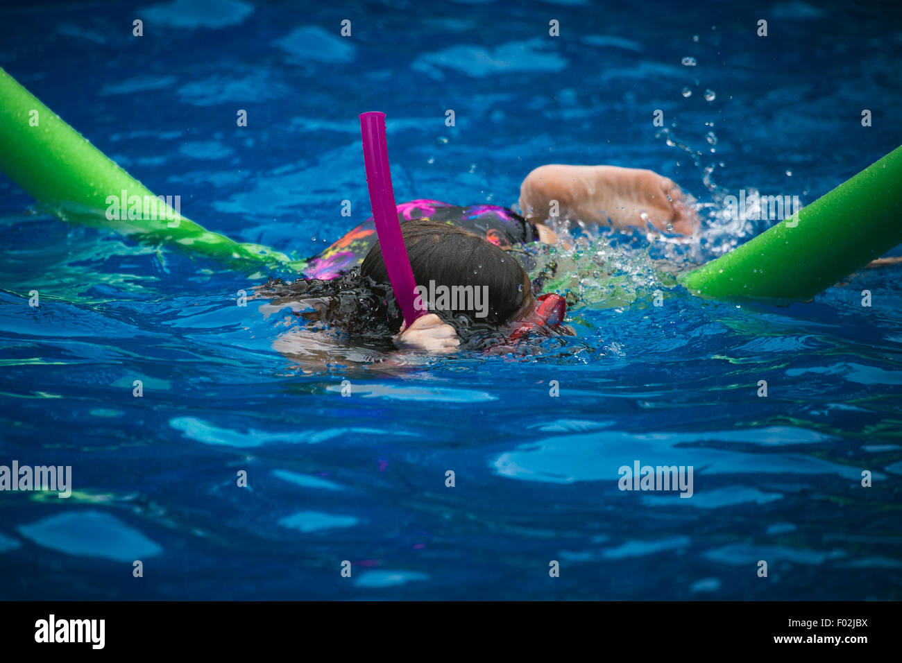 Ein Mädchen in einem Pool mit Brille und Schnorchel schwimmen Stockfoto
