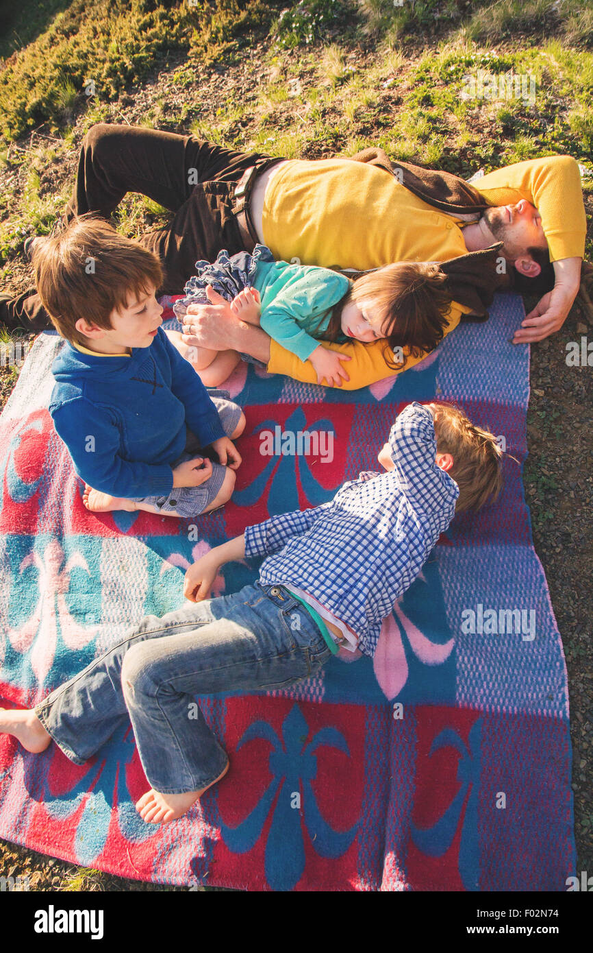 Vater und seinen drei Kindern auf der Picknickdecke liegen Stockfoto