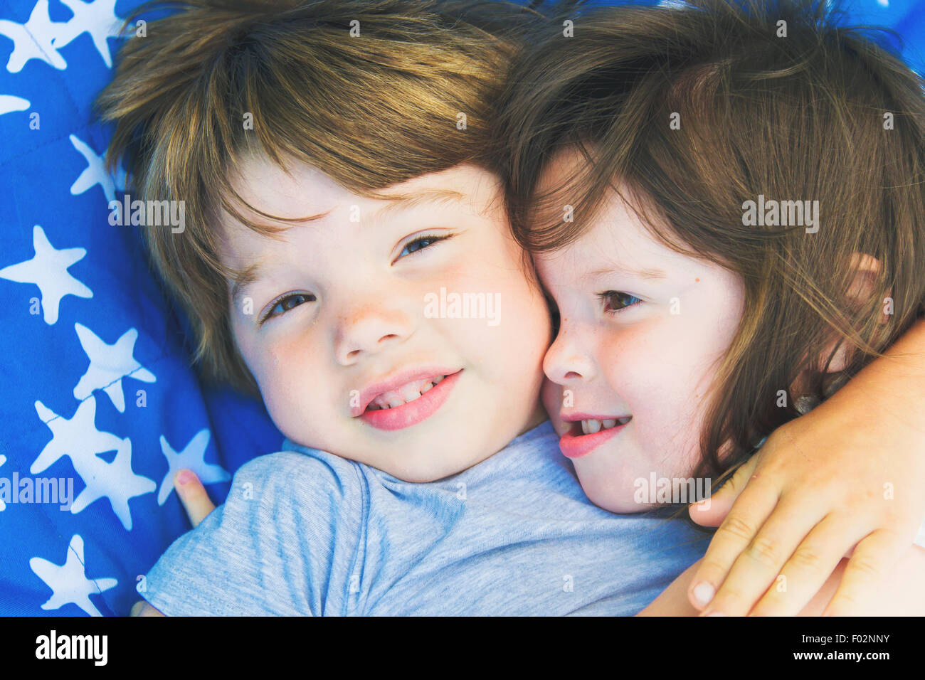 Zwei Kinder liegend auf einer Decke umarmen einander Stockfoto