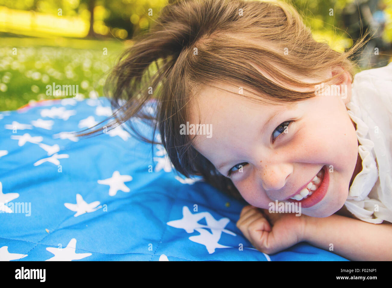 Nahaufnahme eines Mädchens liegend auf einer Decke vor Lachen Stockfoto
