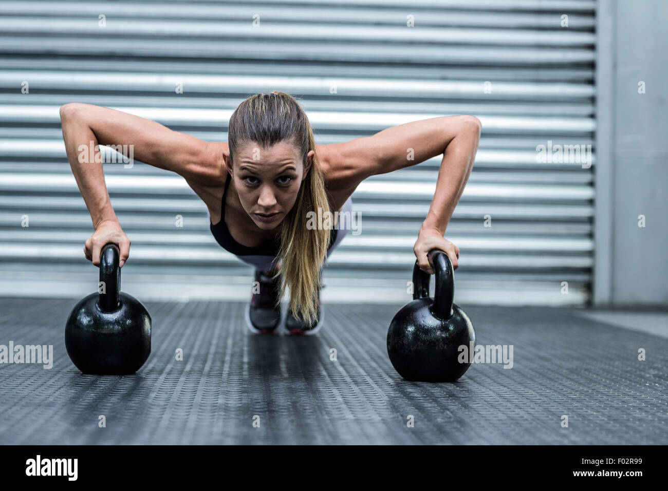 Muskulöse Frau tun Liegestütze mit kettlebells Stockfoto
