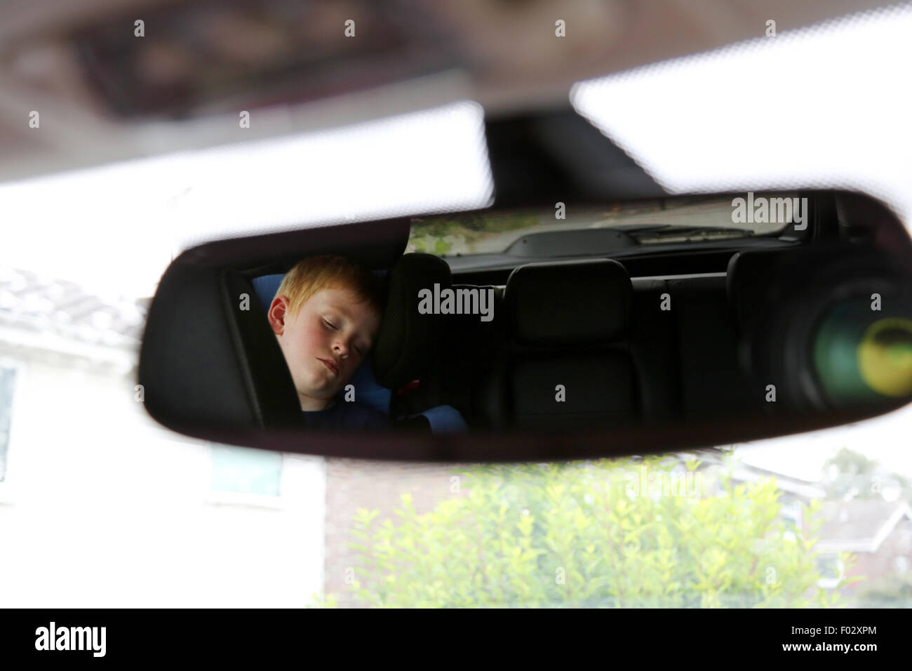 Ein kleines Kind schläft in einem das Heck des Autos im Rückspiegel betrachtet Stockfoto
