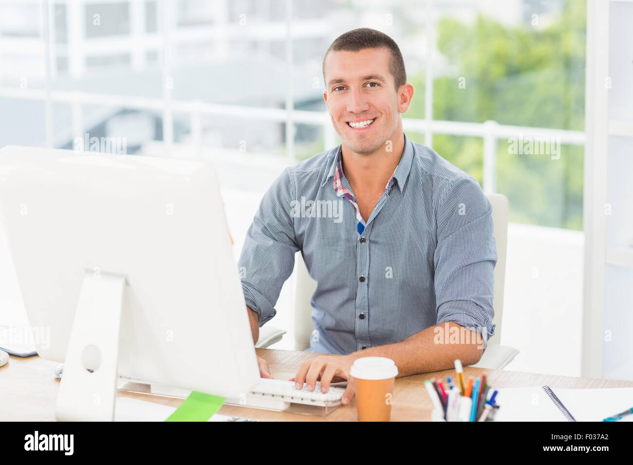 Gut aussehend lächelnd Geschäftsmann auf einem Computer eingeben Stockfoto