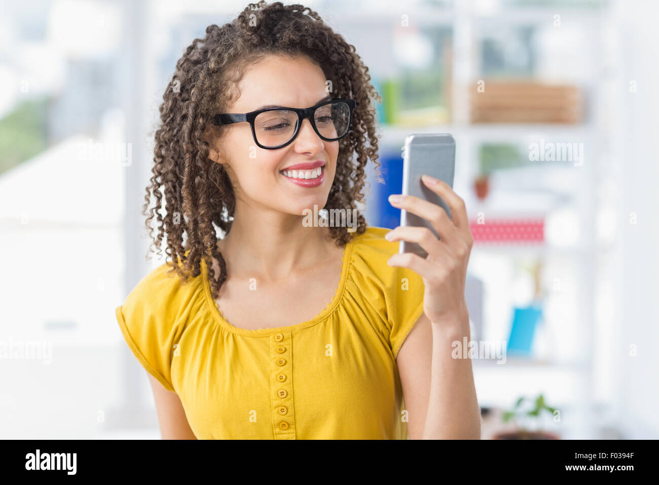 Lächelnde junge Geschäftsfrau, die einen Text senden Stockfoto