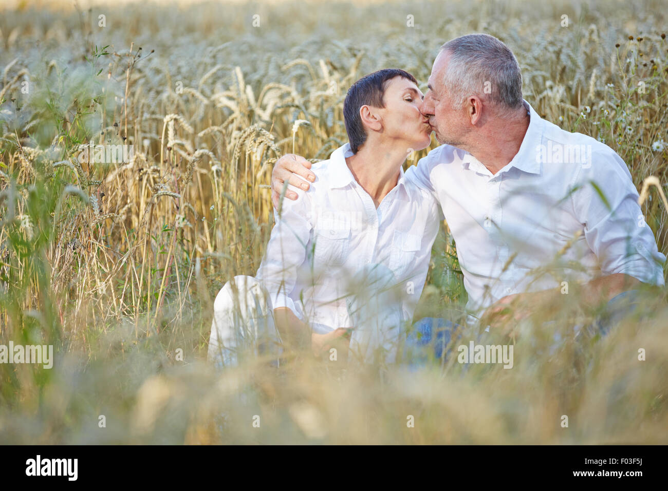 Älteres Paar verliebt küssen in einem Weizenfeld Stockfoto