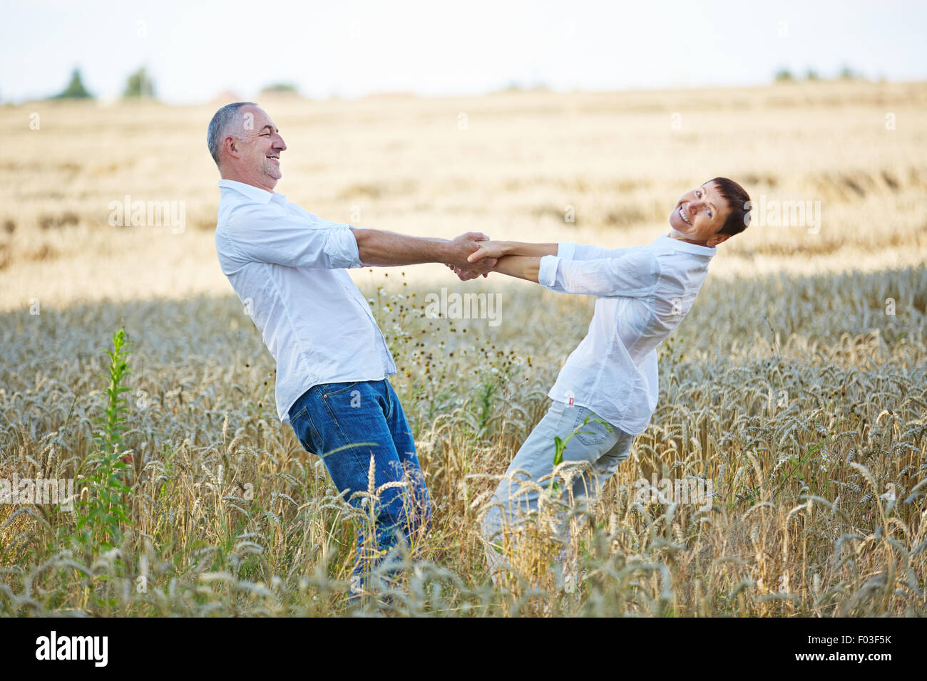 Gerne älteres paar tanzen im Sommer in einem Weizenfeld Stockfoto