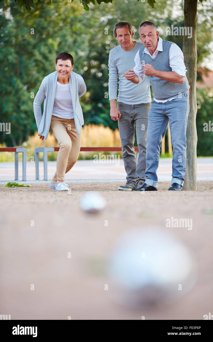 Frau, spielen Boule mit Gruppe von Senioren im Sommer und wirft den ball Stockfoto