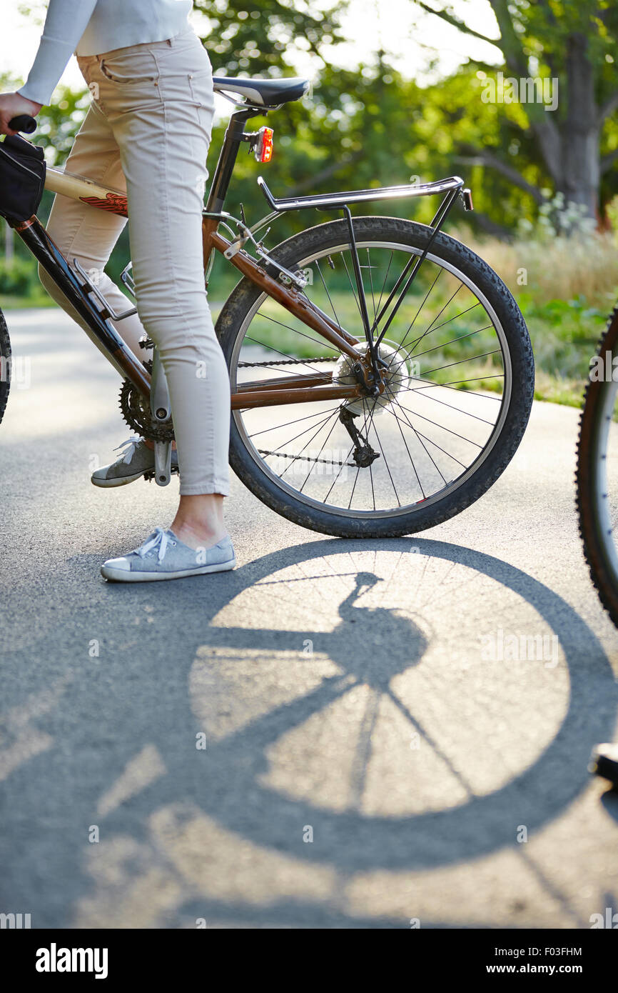 Reifen des Fahrrades auf einer Straße mit Beine einer Frau Stockfoto