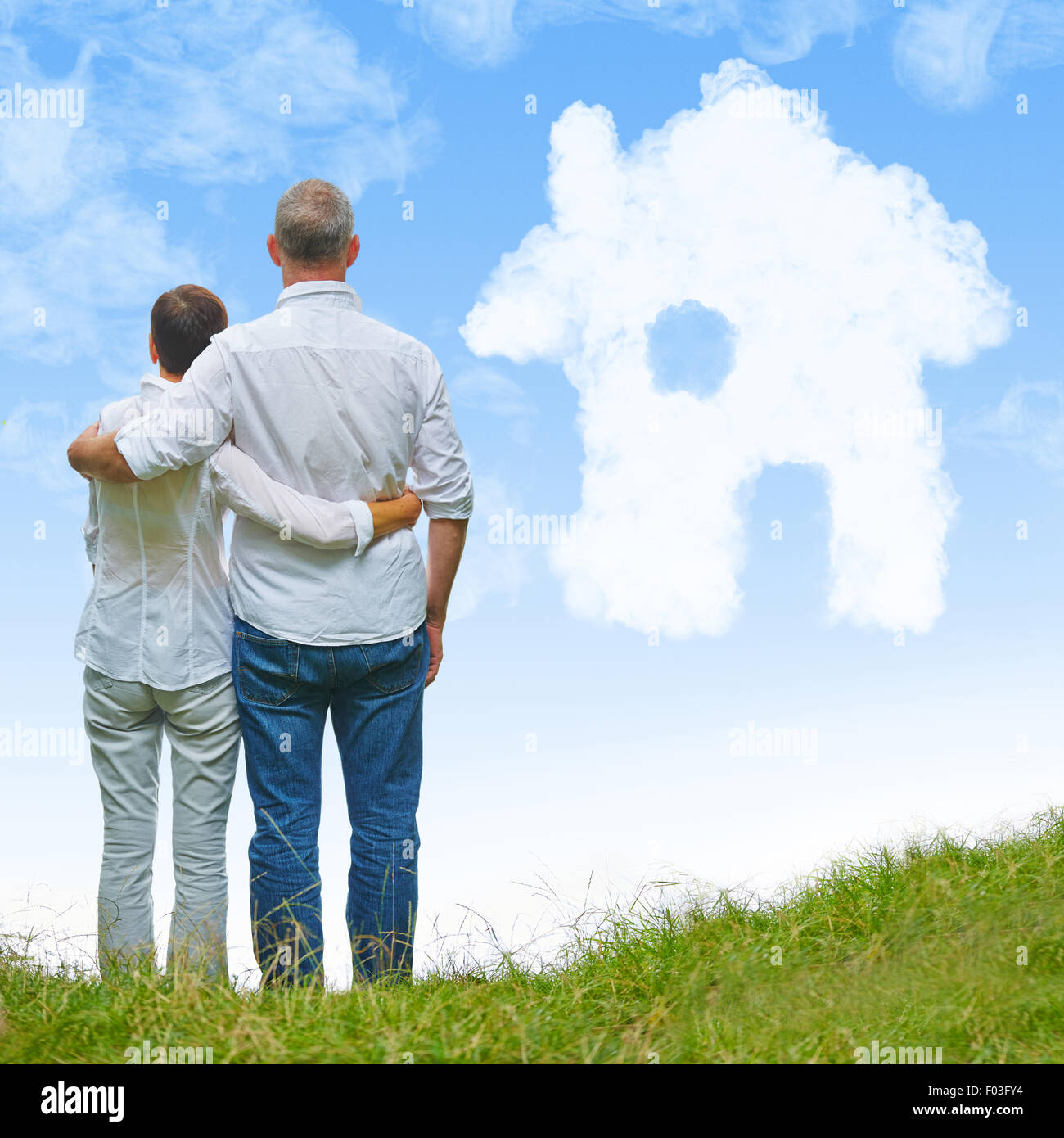 Älteres Paar auf weißer Traumhaus aus Wolken am blauen Himmel Stockfoto