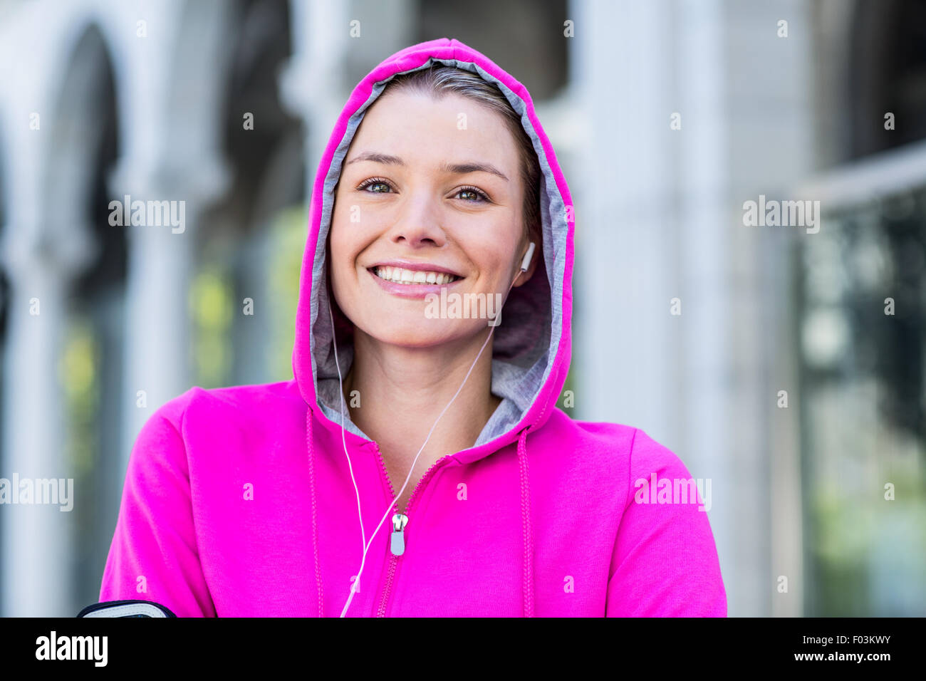 Porträt einer Frau mit einer rosa Jacke setzen ihre Kopfhörer Stockfoto