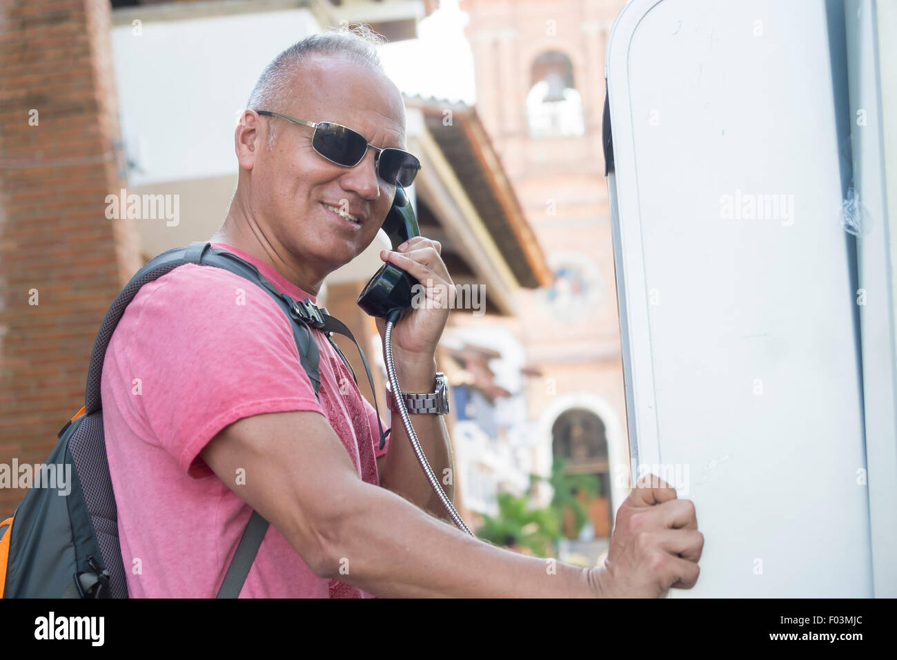 Tourismus in Puerto Vallarta, Mexiko. Mann, 55 Jahre alt, hispanische Ethnizität, Rucksack, mit öffentlichen Telefonzelle. Stockfoto