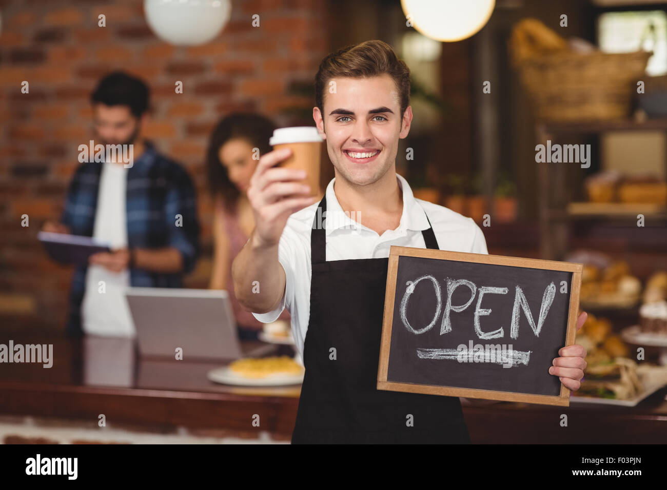 Lächelnd Barista mit Take-away-Becher und Schild "geöffnet" Stockfoto