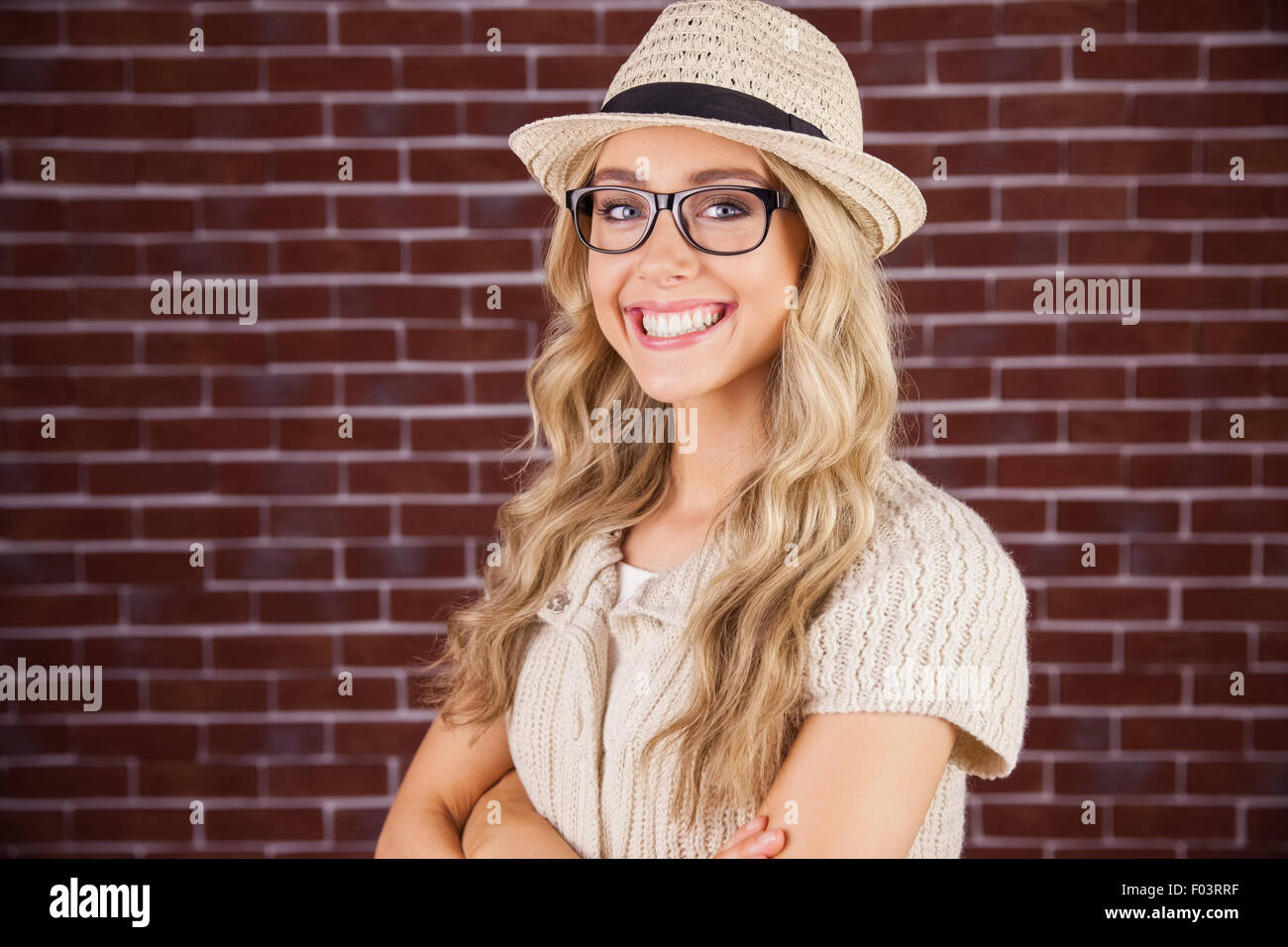 Wunderschöne lächelnde blonde Hipster mit verschränkten Armen Stockfoto