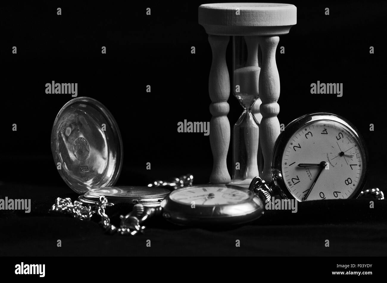 Uhren und Sanduhr auf schwarzem Samt. Stockfoto