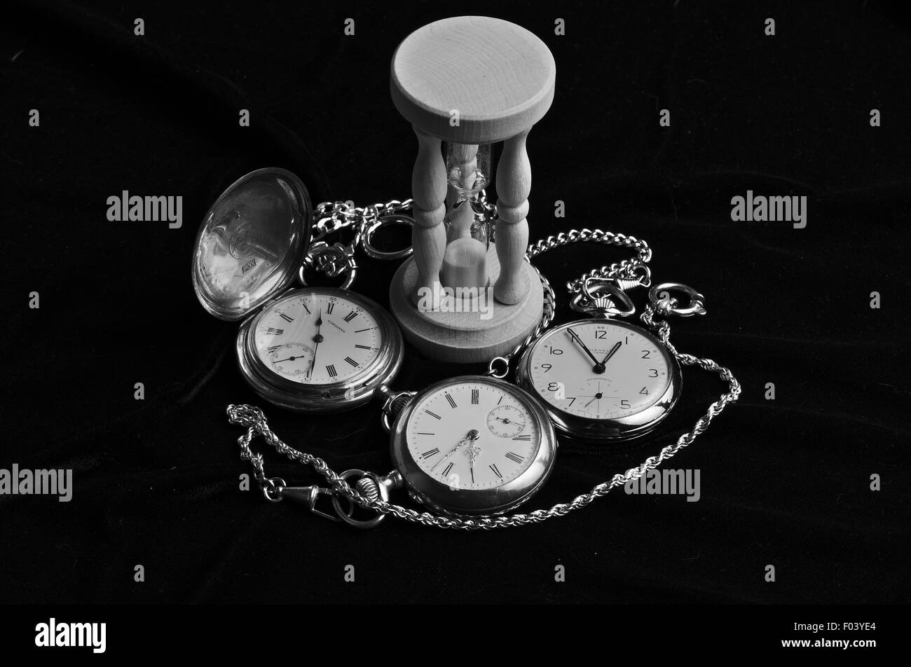 Uhren und Sanduhr auf schwarzem Samt. Stockfoto