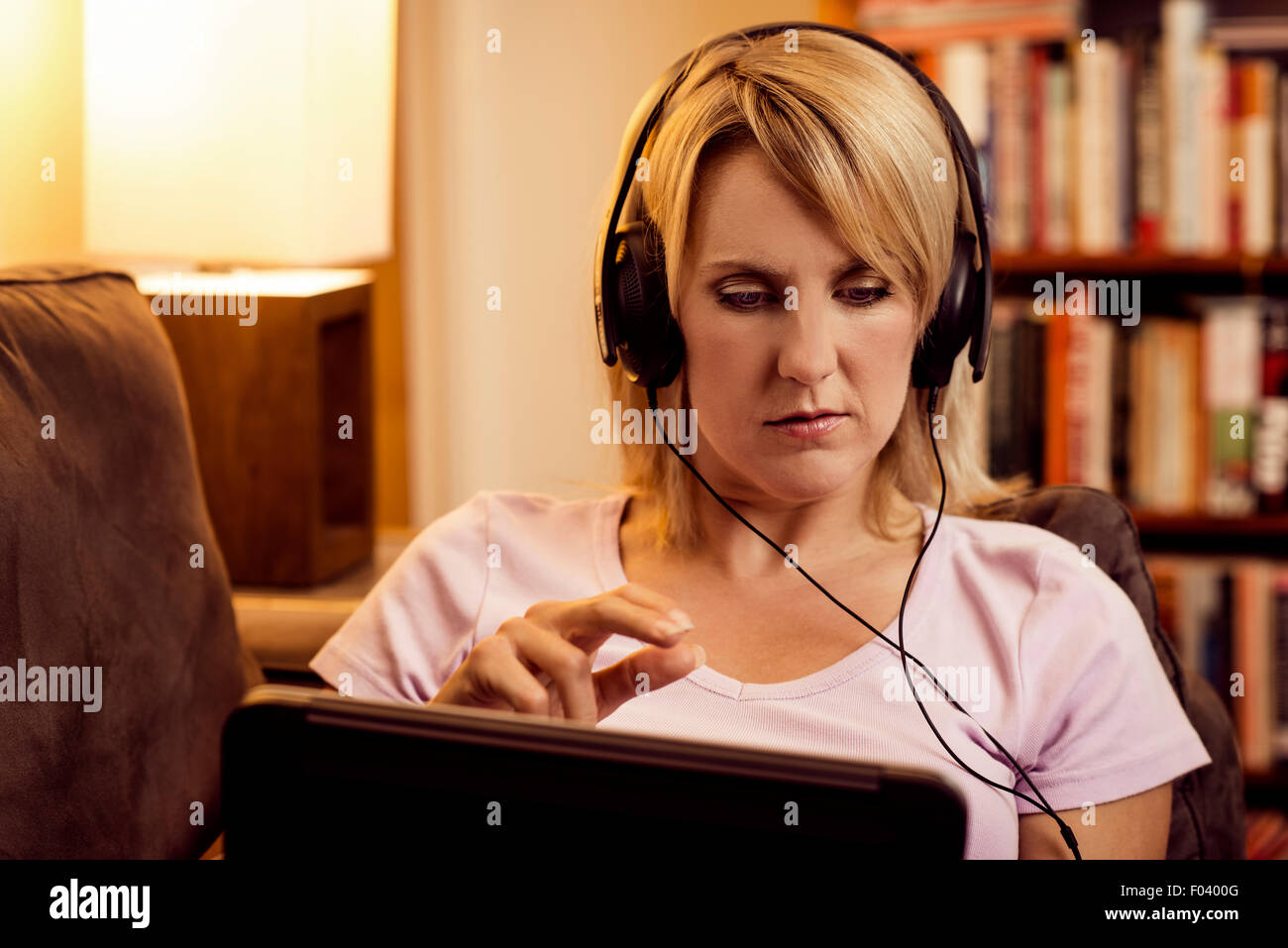 Frau mit Tablet und Kopfhörer zu Hause auf sofa Stockfoto