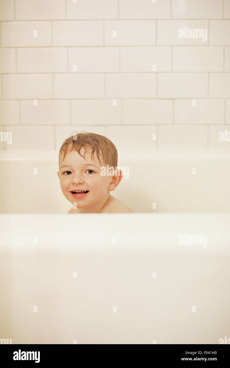 Kleiner Junge sitzt in der Badewanne Baden, lächelnd in die Kamera. Stockfoto