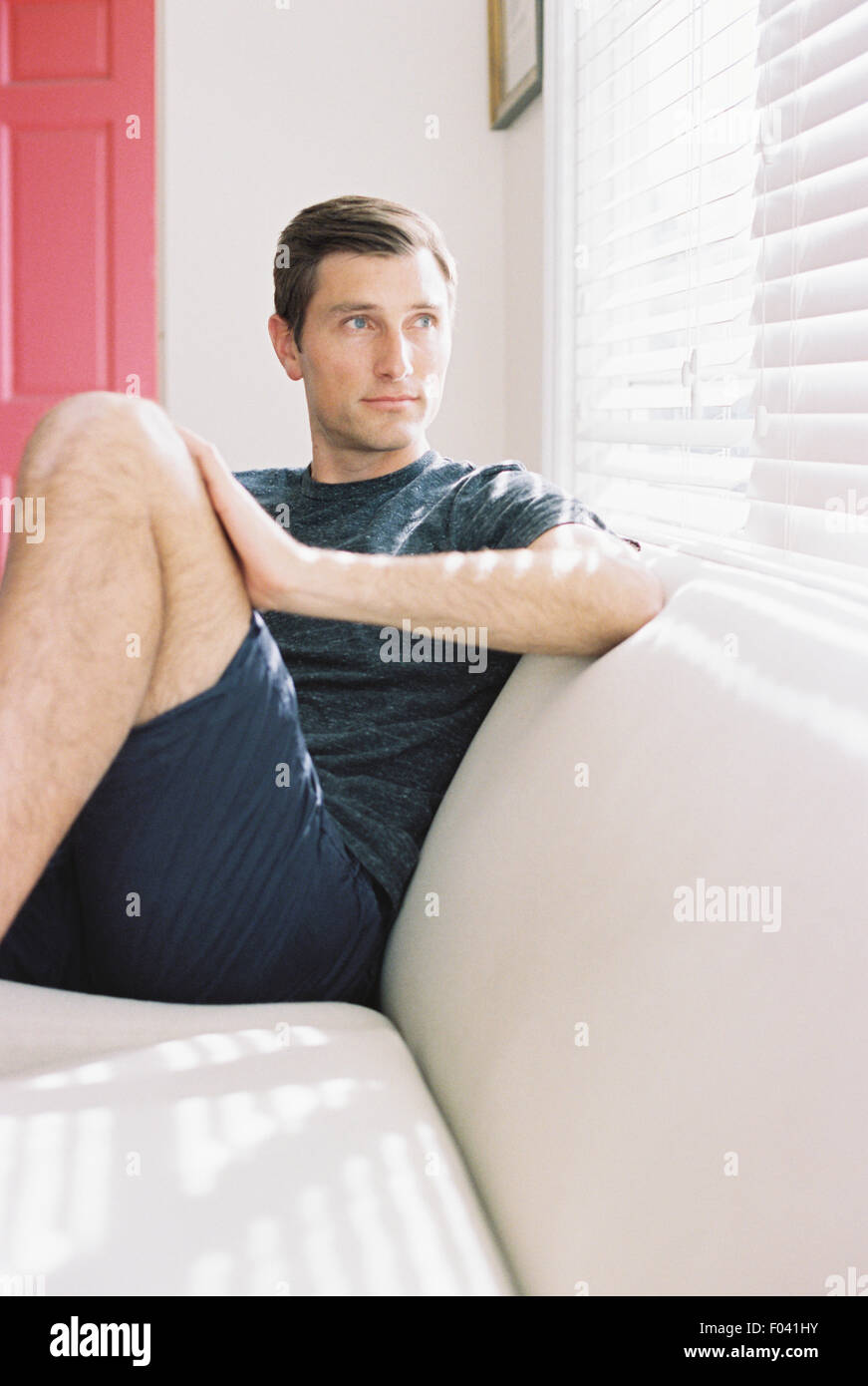 Man sitzt auf einem Sofa von einem Fenster, entspannen. Stockfoto