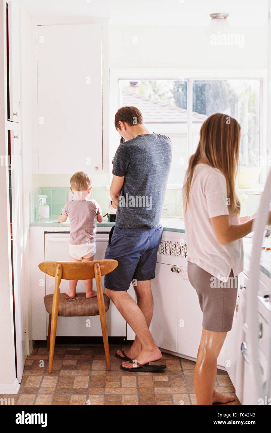 Paar in einer Küche, ihren Sohn auf einem Stuhl neben ihnen stehen. Stockfoto