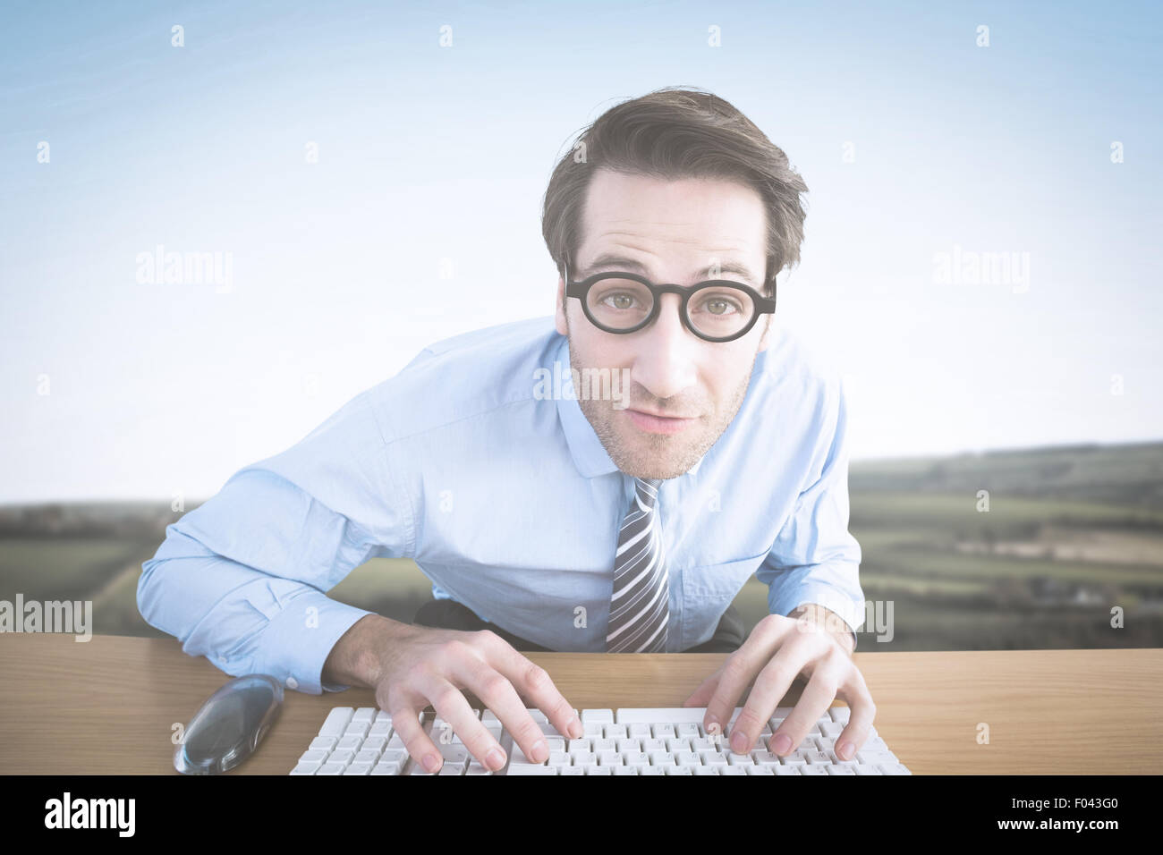 Zusammengesetztes Bild des Kaufmanns Tippen auf seiner Tastatur mit Brille Stockfoto
