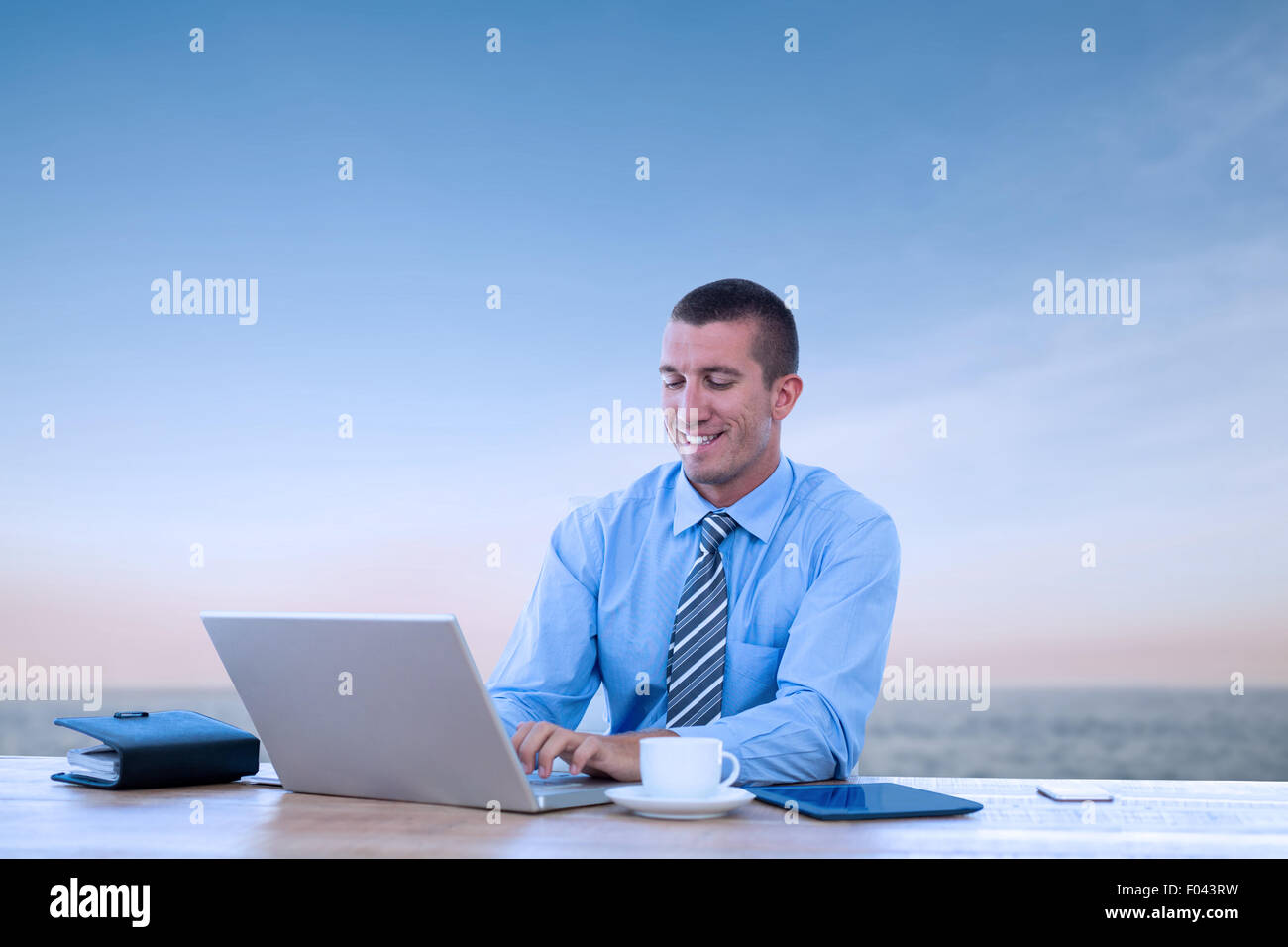 Zusammengesetztes Bild des lächelnden Geschäftsmann mit seinem Laptop arbeiten Stockfoto