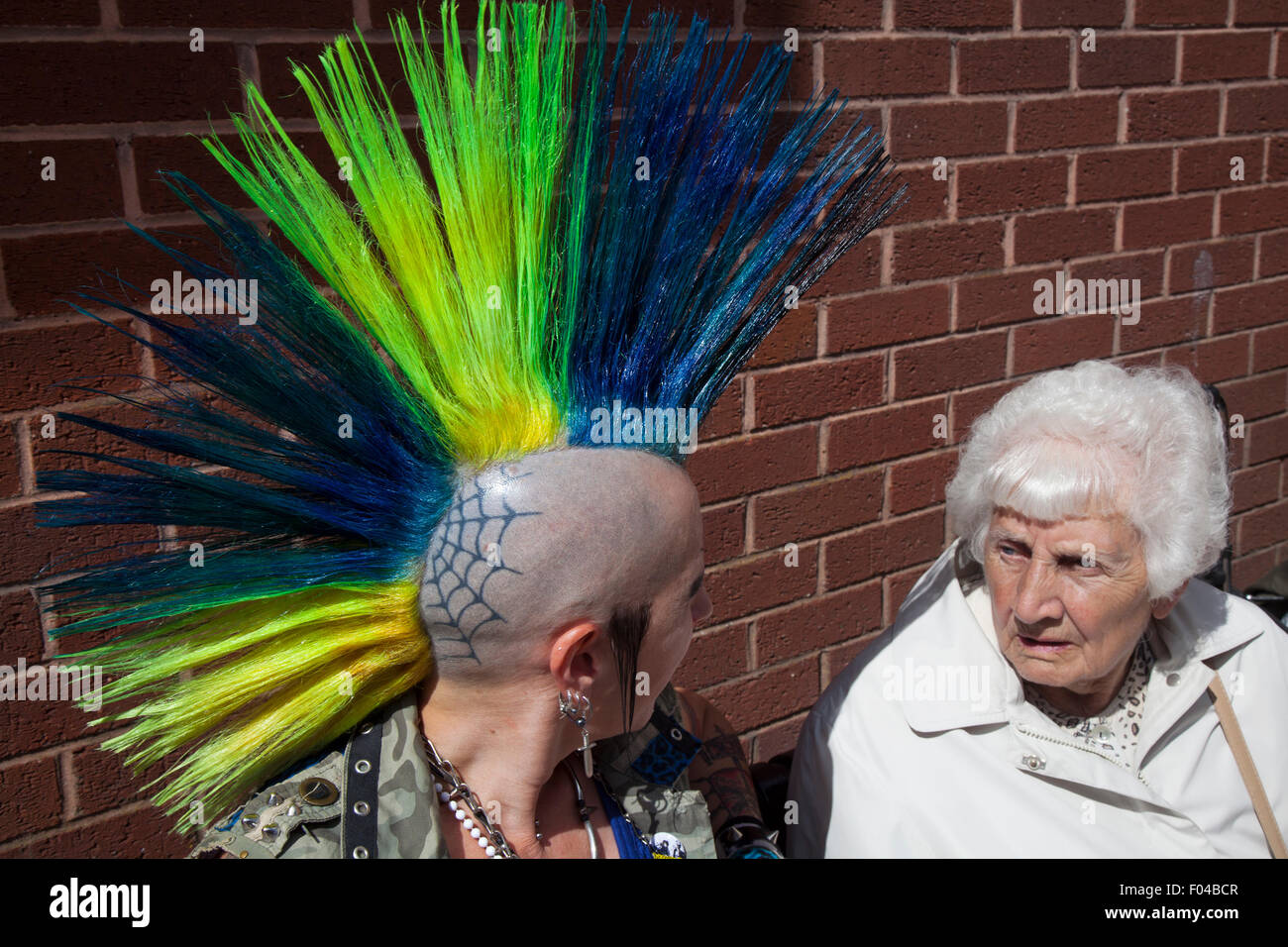 Blackpool, Lancashire, UK. 6. August 2015. Irene Bowker, 88 Jahre alt am Punk Rebellion Festival im Winter Gardens, Gespräche zu einer Frau mit einem tätowierten Kopf und mohican liberty Haarschnitt. Ein Zusammenprall der Kulturen an der berühmten küstenstadt Blackpool als Punks die Teilnahme an der jährlichen Rebellion Festival im Winter Gardens kommen Schulter mit traditionellen Urlauber zu schultern. Ein Mohawk oder Mohican Frisur mit Kopf rasiert. Stockfoto