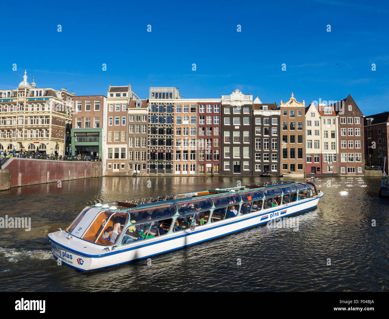 Kreuzfahrtschiff Touristen am Damrak Kanal in Amsterdam, Niederlande, an einem Sommertag. Traditionelle Häuser im Hintergrund. Stockfoto