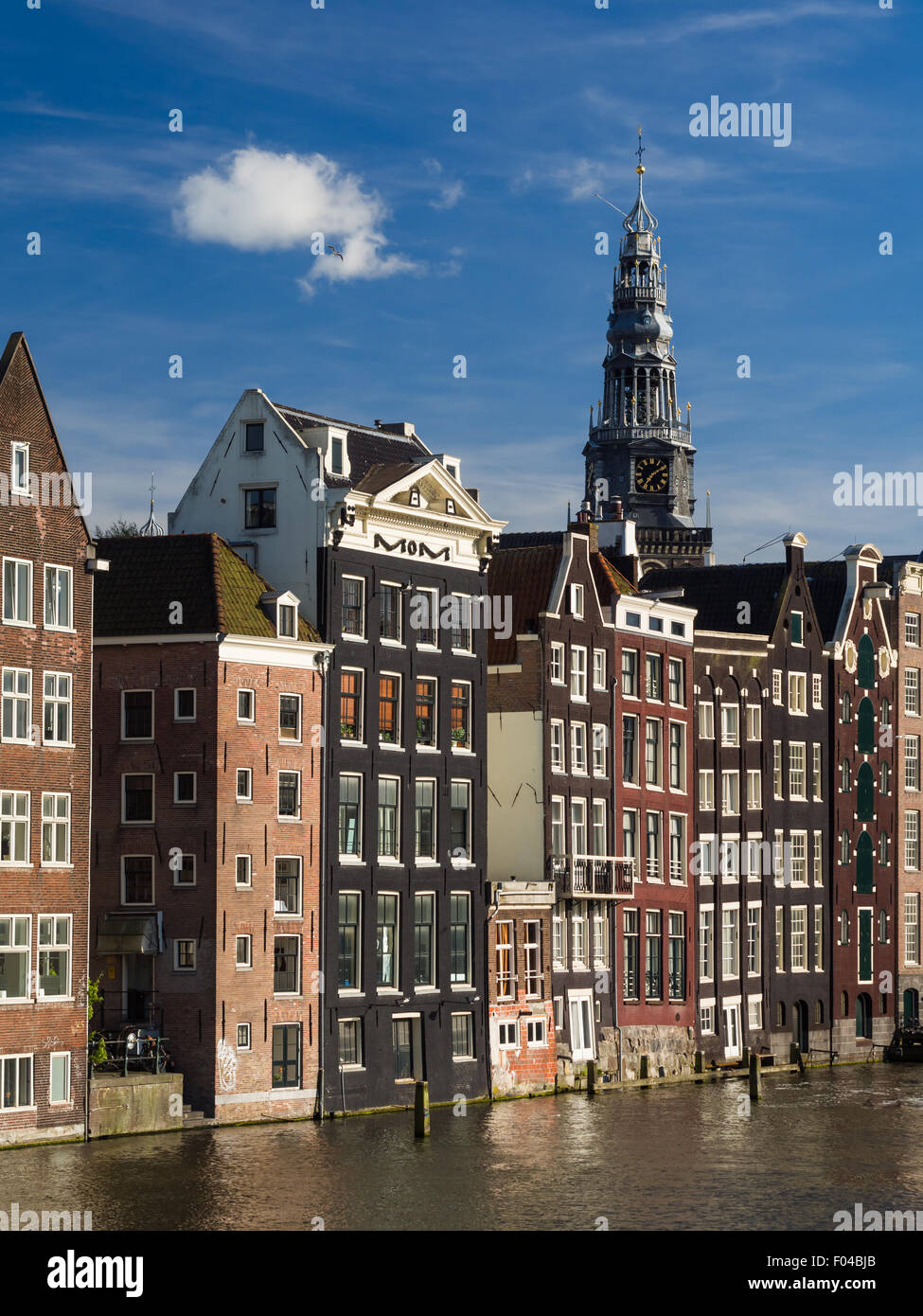 Traditionelle Häuser über Damrak Kanal in der alten Stadt von Amsterdam, Niederlande. Turm der Oude Kirche im Hintergrund. Stockfoto