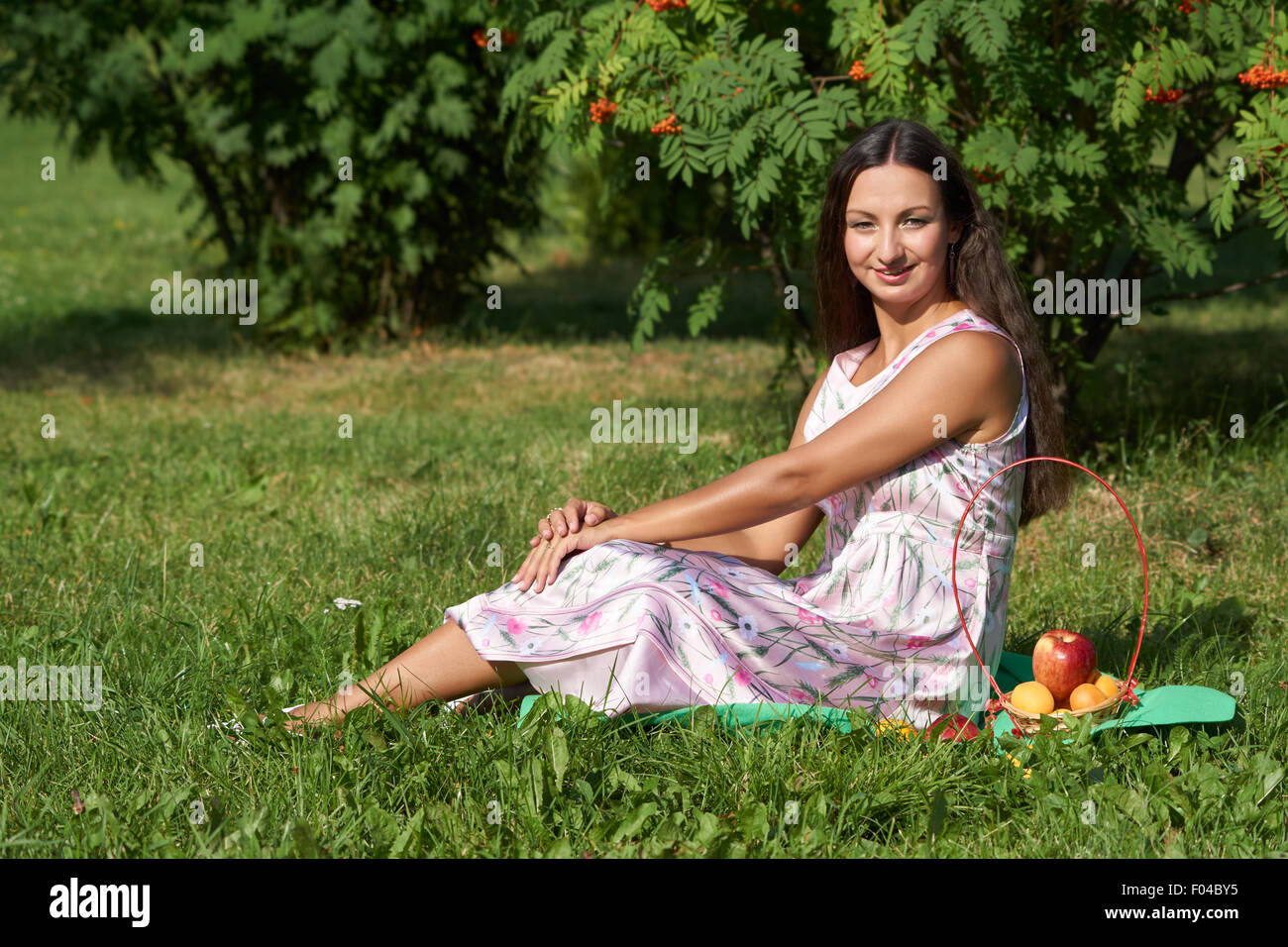 Eine Brünette glückliches Mädchen sitzt auf der Wiese des Parks und hat Picknick Stockfoto