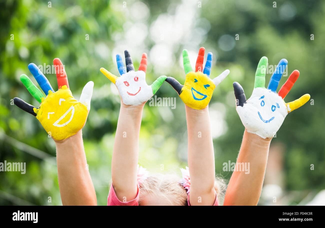 Farbige Hände mit Lächeln in bunten Farben vor grünen Sommer Hintergrund gemalt. Lifestyle-Konzept Stockfoto