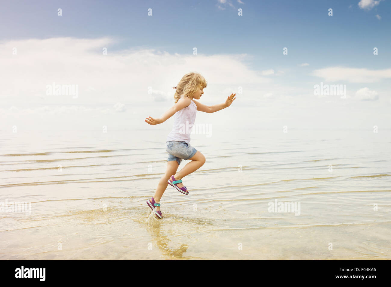 Kleines Mädchen läuft Strand Ufer Spritzwasser Stockfoto