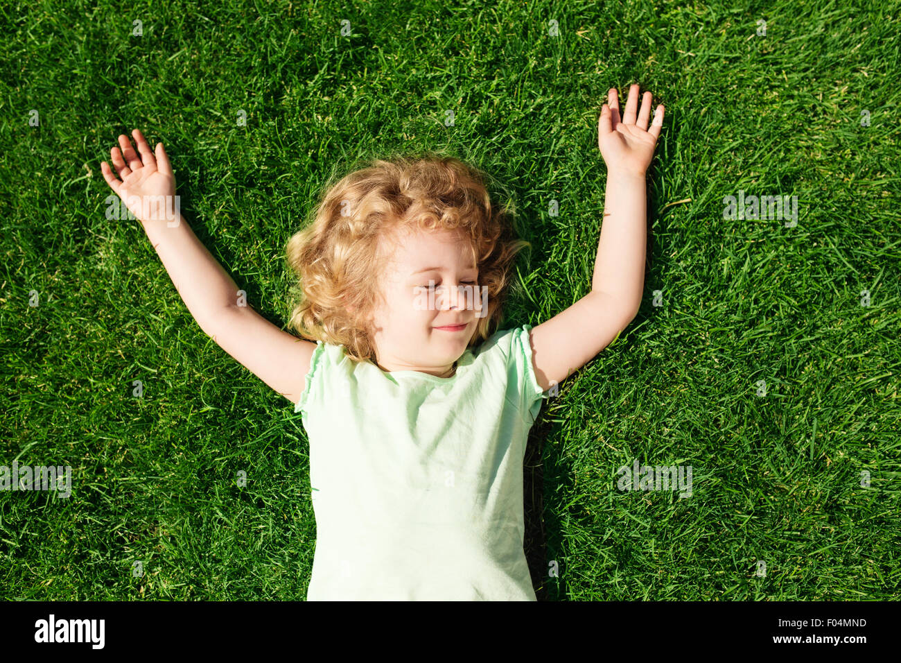 Entzückendes kleine Mädchen liegen auf dem Rasen, Ansicht von oben träumen Stockfoto