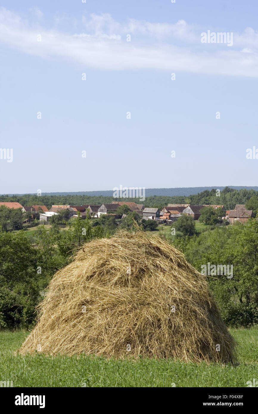 Hay Stack mit Dorf hinter Stockfoto