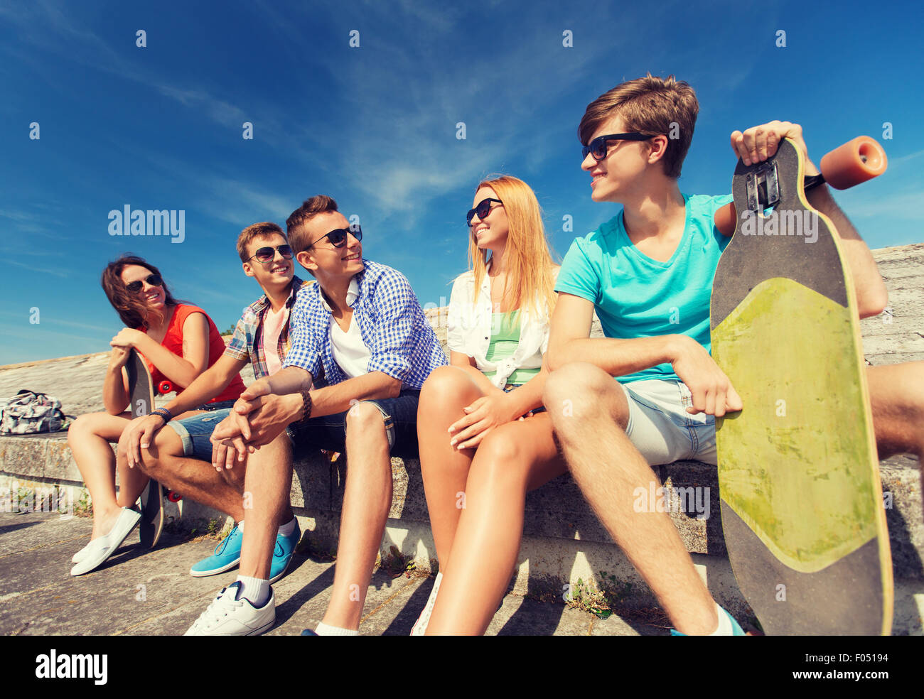 Gruppe von lächelnden Freunde sitzen auf Stadtstraße Stockfoto