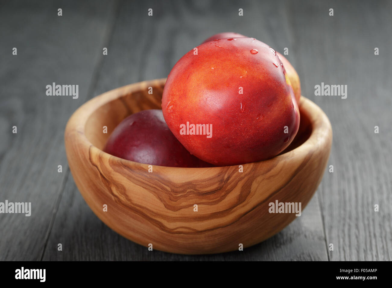 Nektarinen in Oliven Holz Schüssel auf Eichentisch Stockfoto