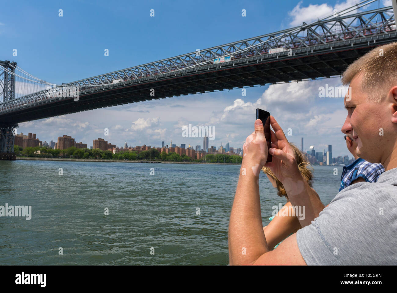 Malerische USA, New York City, NY, Touristen besuchen außerhalb am East River, Fähre, Manhattan Bridge, Mann Fotografieren mit Iphone Smartphone Stockfoto
