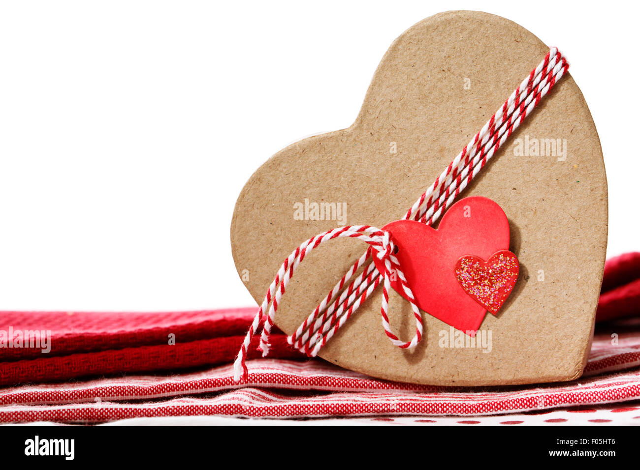 Herzförmige Geschenkbox mit Herz-Tag auf roten Tischdecke Stockfoto
