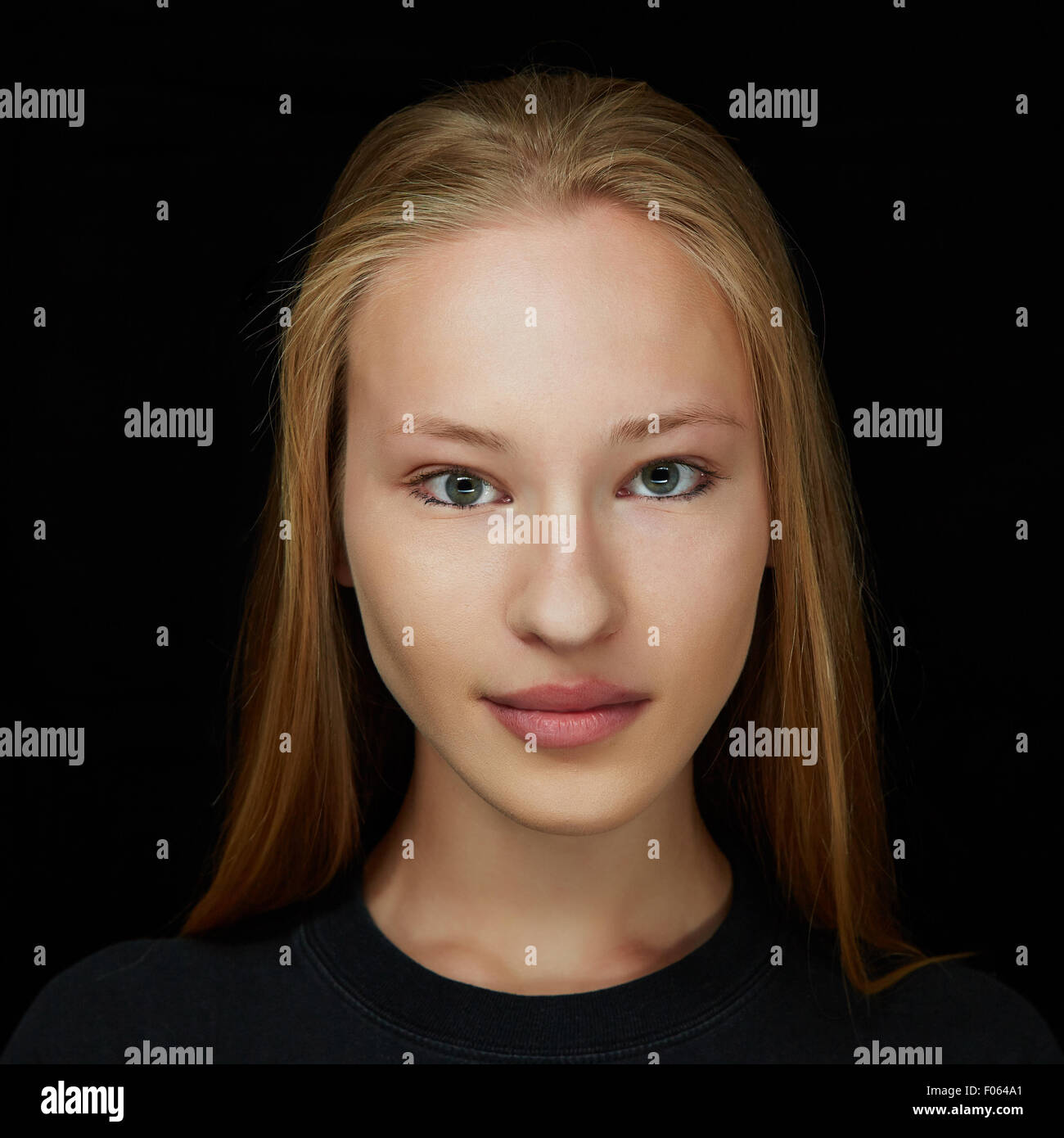 Gesicht einer jungen attraktiven blonden Frau in Vorderansicht auf dunklem Hintergrund Stockfoto